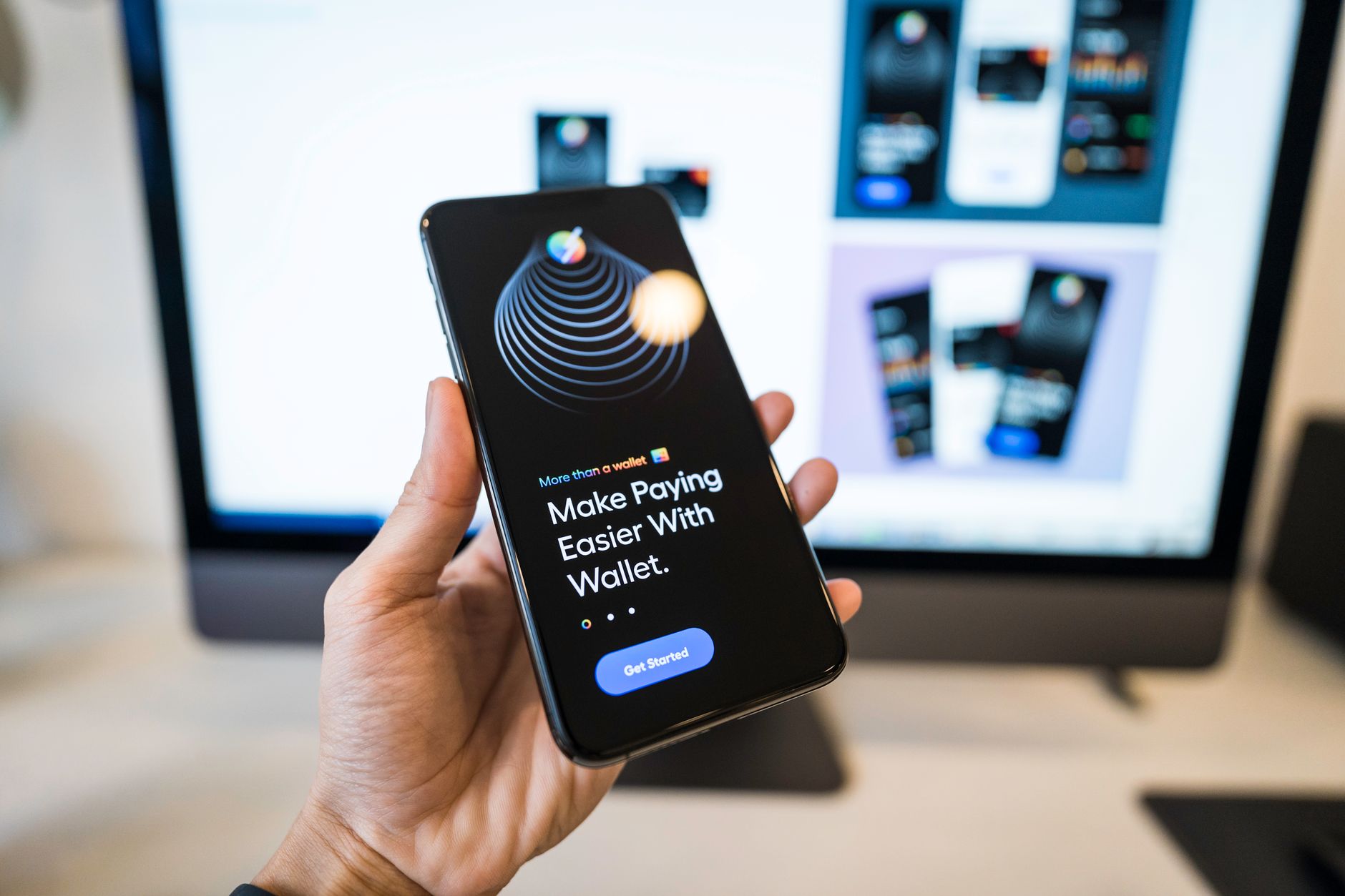Mobile wallet app held in front of a design workstation